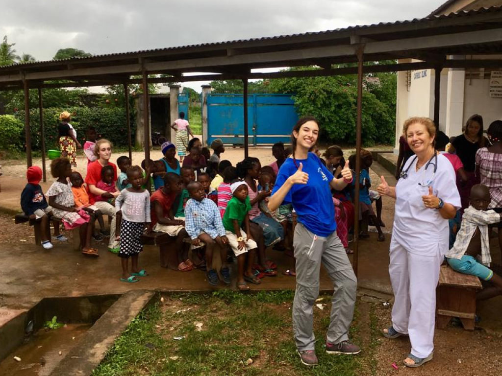 Dos voluntarias y un grupo de niños sentados en bancos